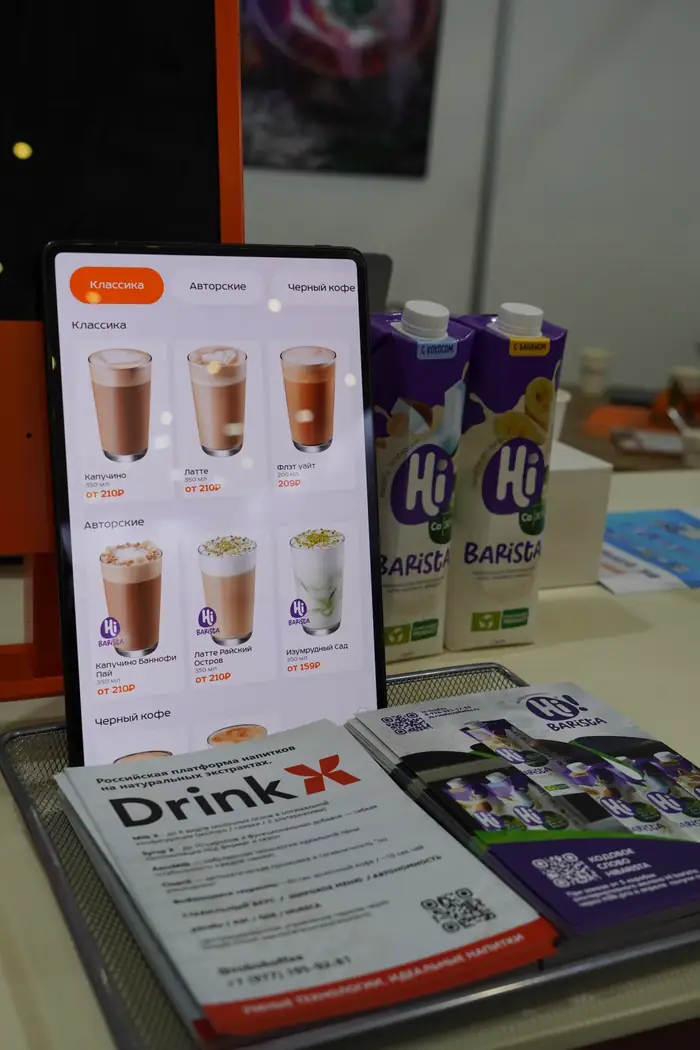 Планшет с меню напитков DrinkX рядом с упаковками барista-молока