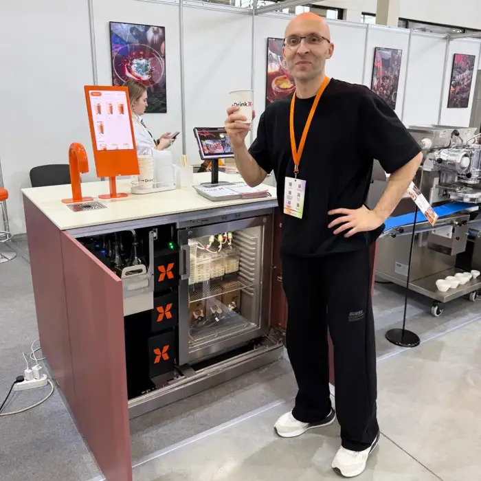 Открытая станция DrinkX с модулями и холодильником, рядом стоит основатель компании