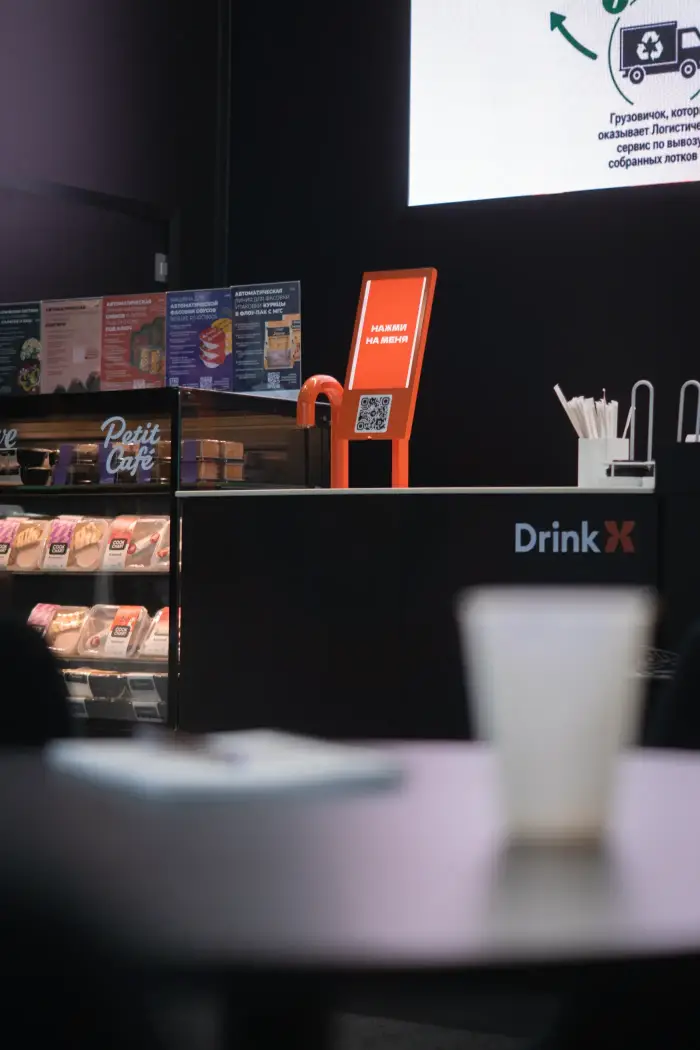 Оранжевый экран заказа и кран DrinkX на выставочном стенде с витриной