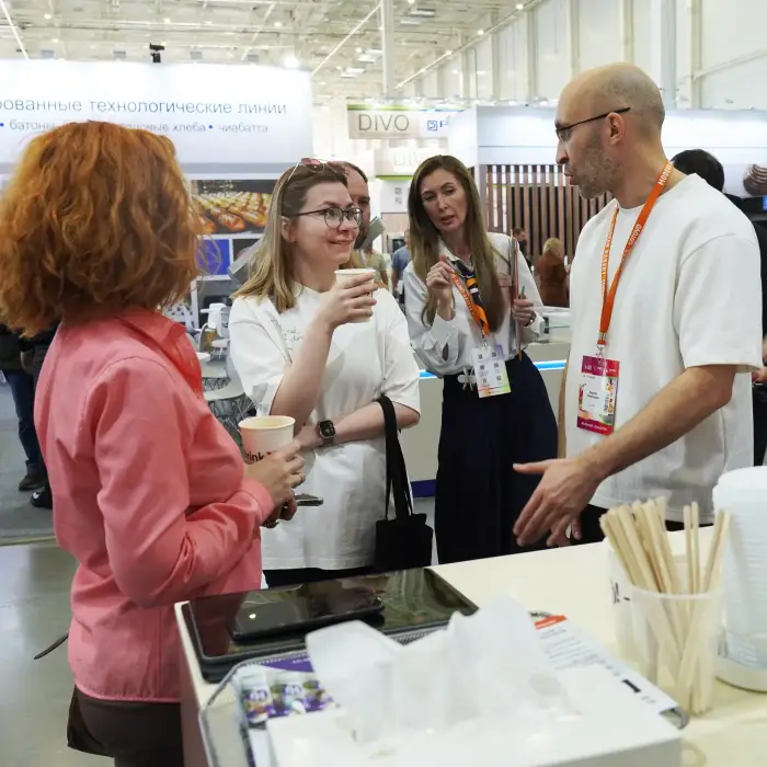 Основатель DrinkX разговаривает с посетителями выставки, у всех в руках стаканы с кофе